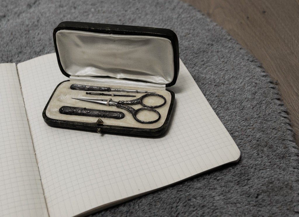 A sewing set with silver chiseled tools in a satin box