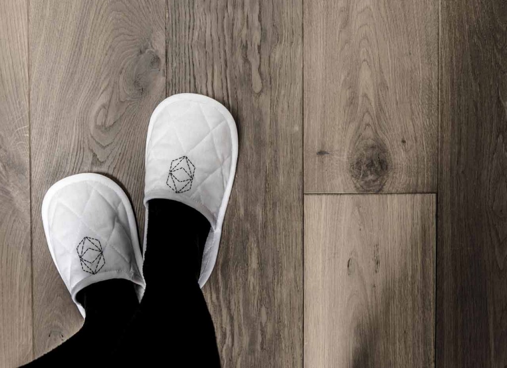 Pantoufles blanches brodées sur parquet en bois