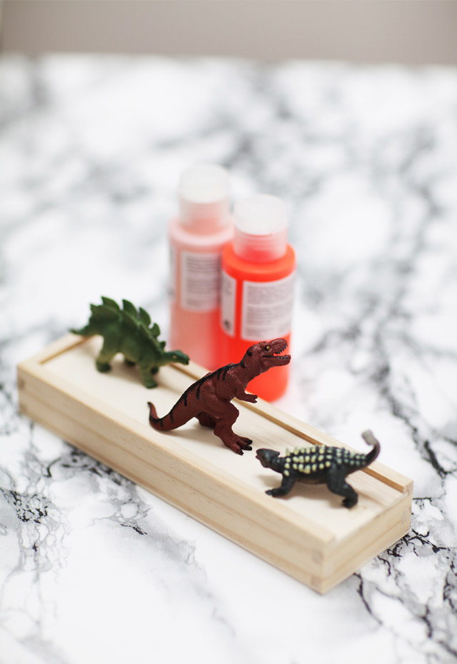 Trois petits dinosaures de couleur sur une boite en bois