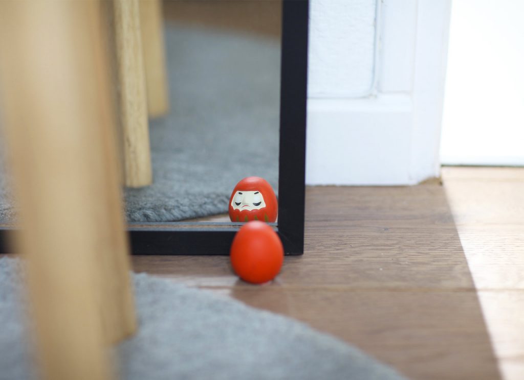 Japanese Daruma ou Bodhidharma looking into the mirror 