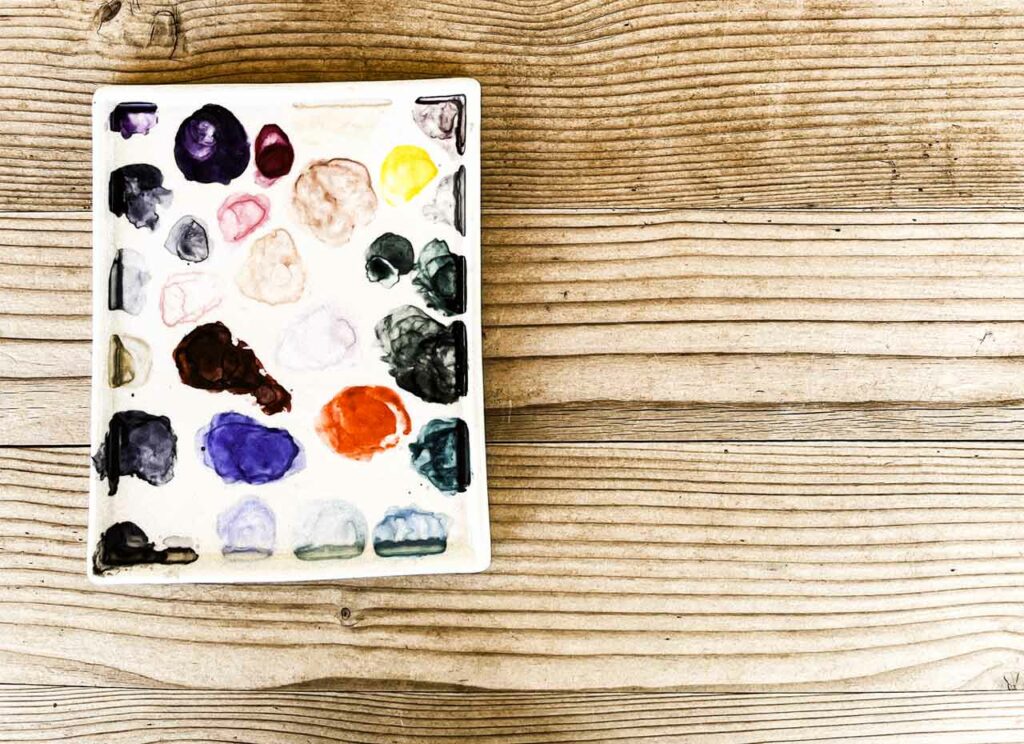 Recherche d'une gamme de couleur à l'aquarelle sur une palette en céramique rectangulaire blanche.